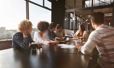 Een groep mensen rondom een tafel waar ze uitleg krijgen over de Projectmanagement aanpak van Advisie